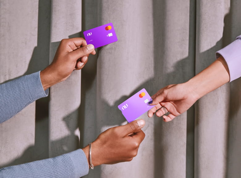3 brazos humanos sosteniendo tarjetas de crédito y débito Nu
